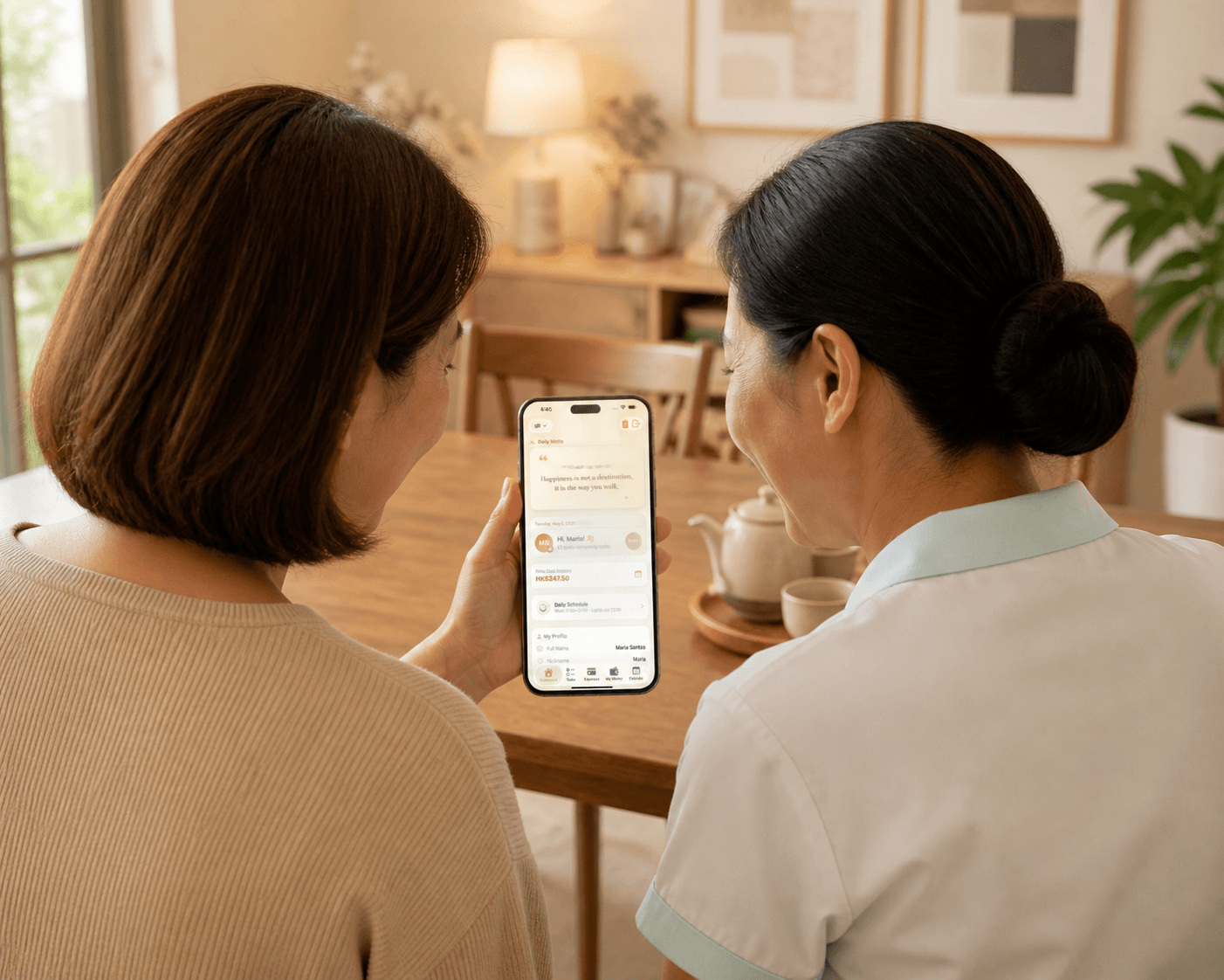 Two women sitting at a wooden table, looking at a mobile screen with a schedule and tasks